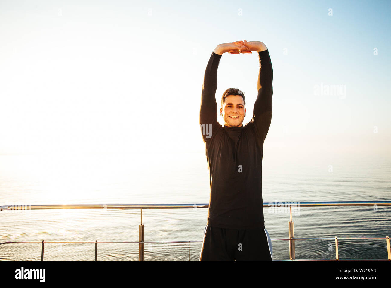 portrait of guy stretching on the beach, preparing for running Stock Photo