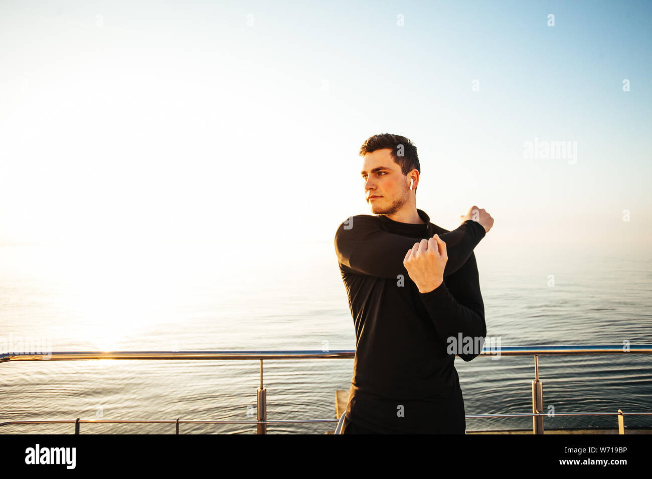 portrait of guy stretching on the beach, preparing for running Stock Photo