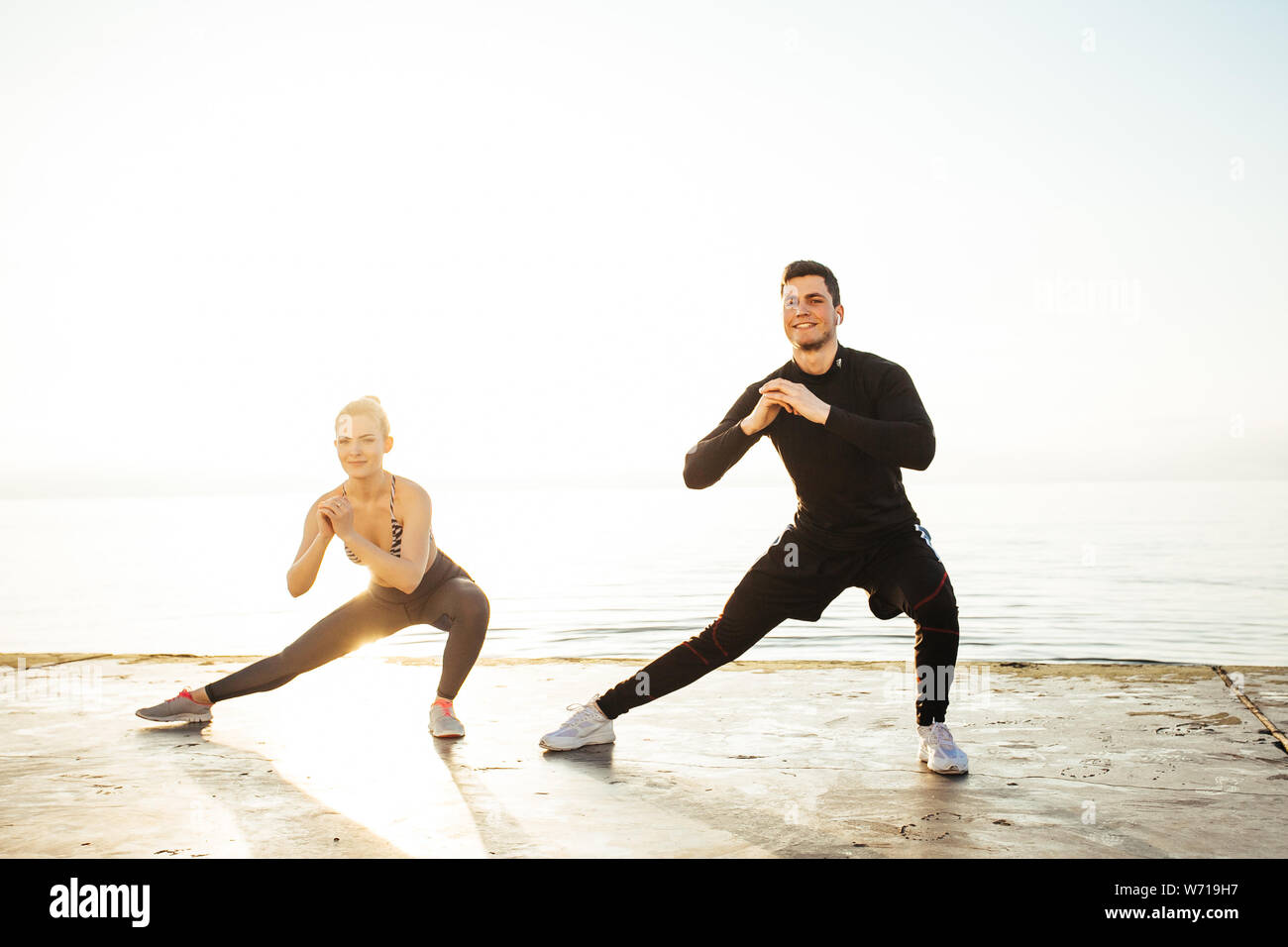 Fitness, sport, friendship and lifestyle concept - couple exercising at the beach Stock Photo