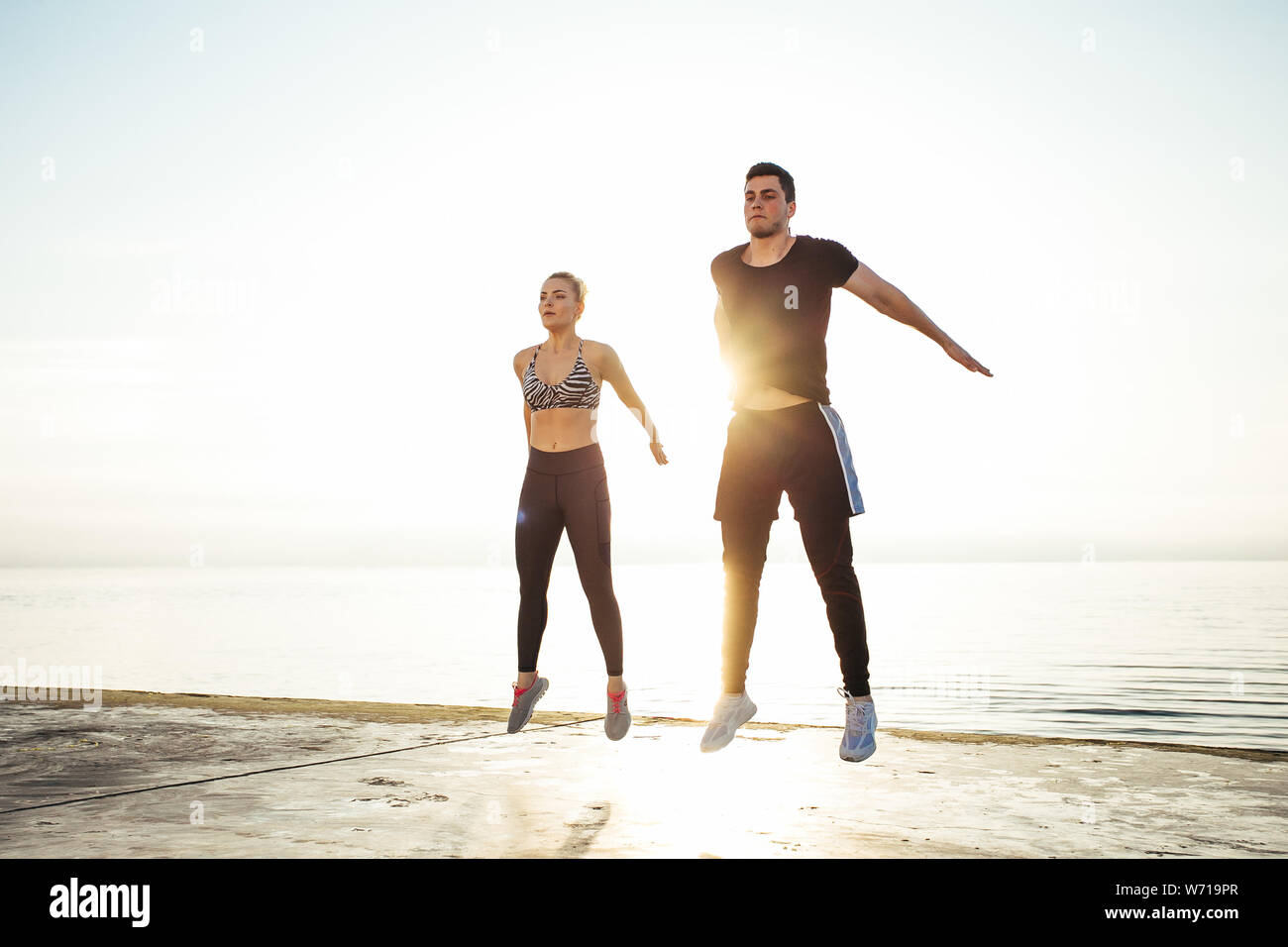 Fitness, sport, friendship and lifestyle concept - couple exercising at the beach Stock Photo