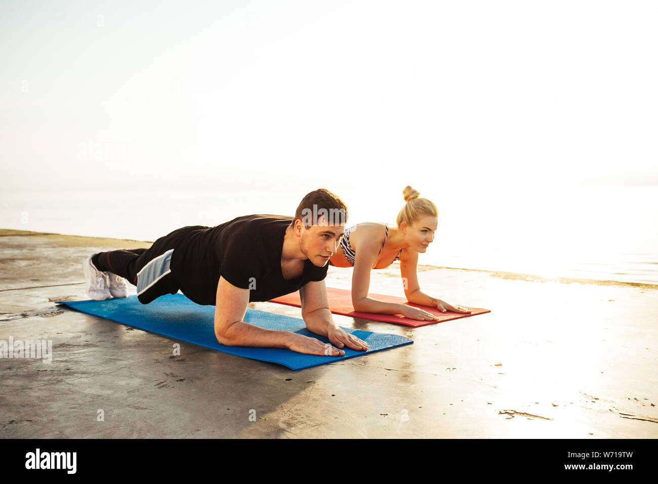 Fitness, sport, friendship and lifestyle concept - couple exercising at the beach Stock Photo