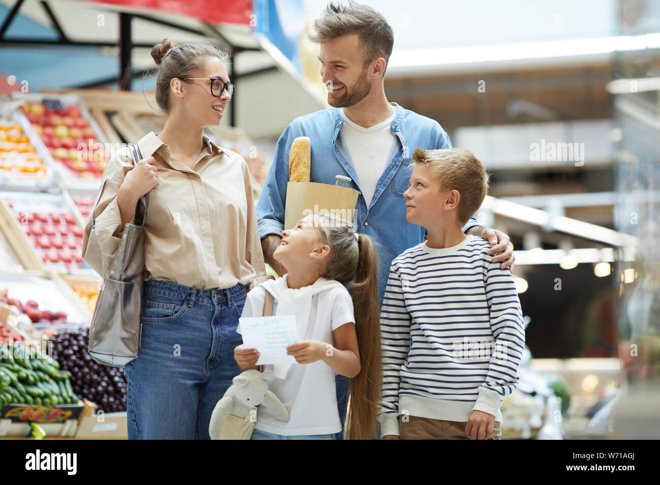 Portrait of contemporary family with two kids shopping at farmers market, copy space Stock Photo