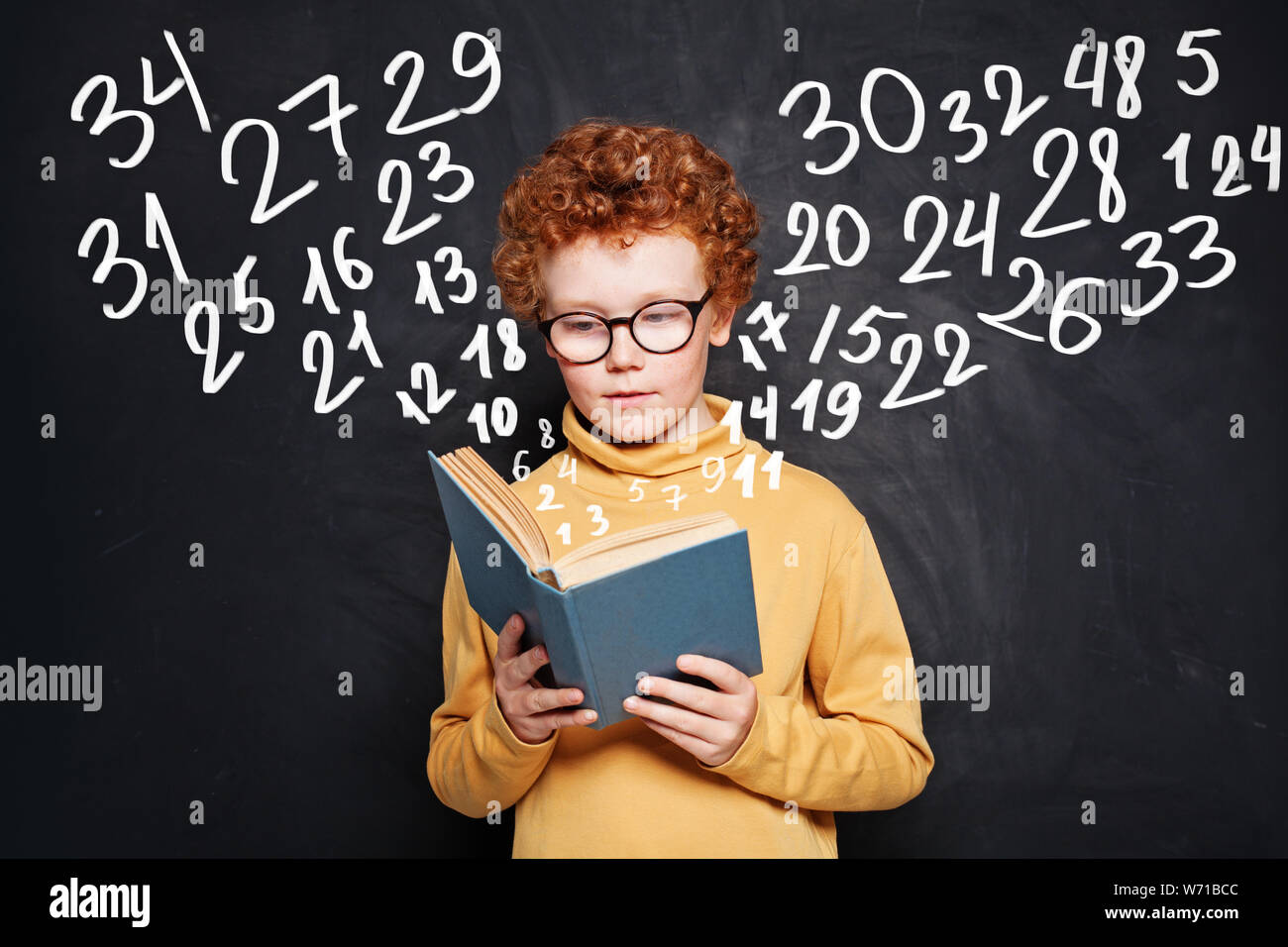 Kid reading a book on chalkboard background Stock Photo