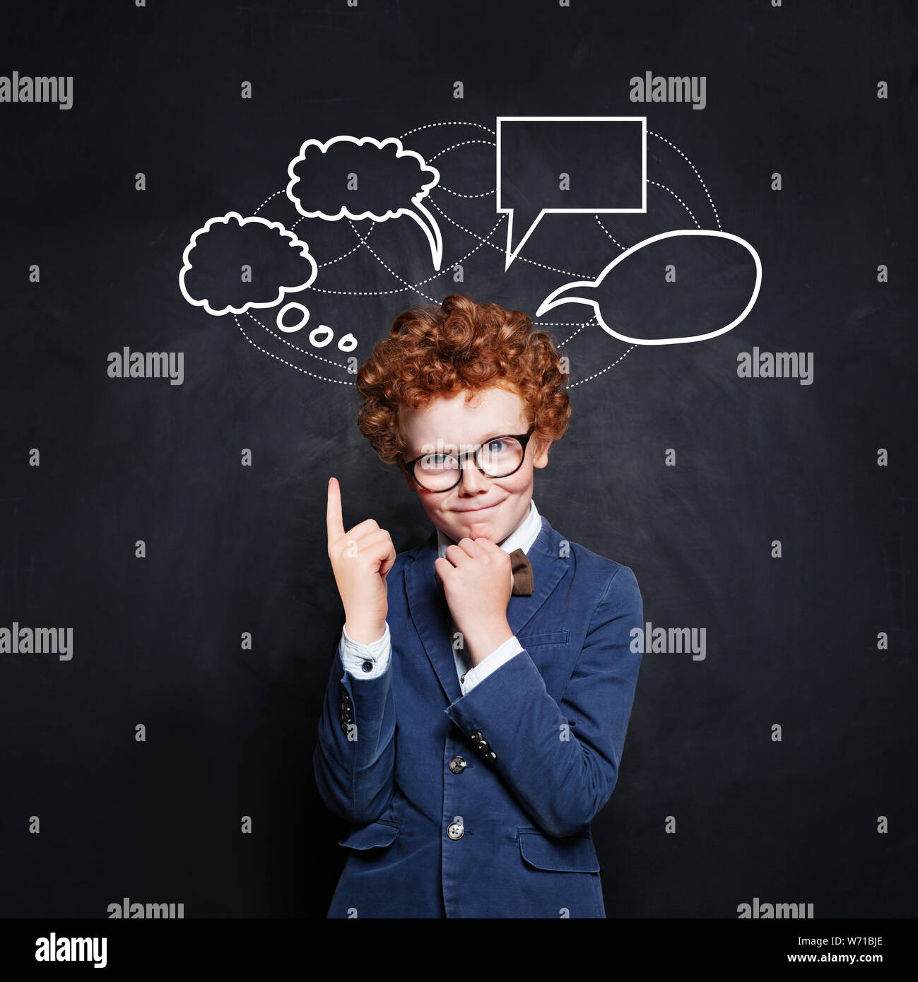 Smart schoolboy pointing at empty speech clouds bubbles on chalkboard background Stock Photo