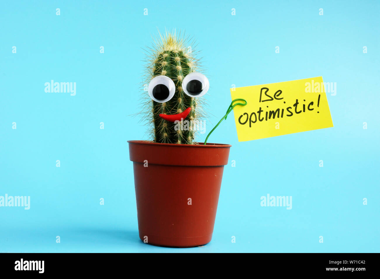 Small cactus is holding sign Be optimistic. Stock Photo