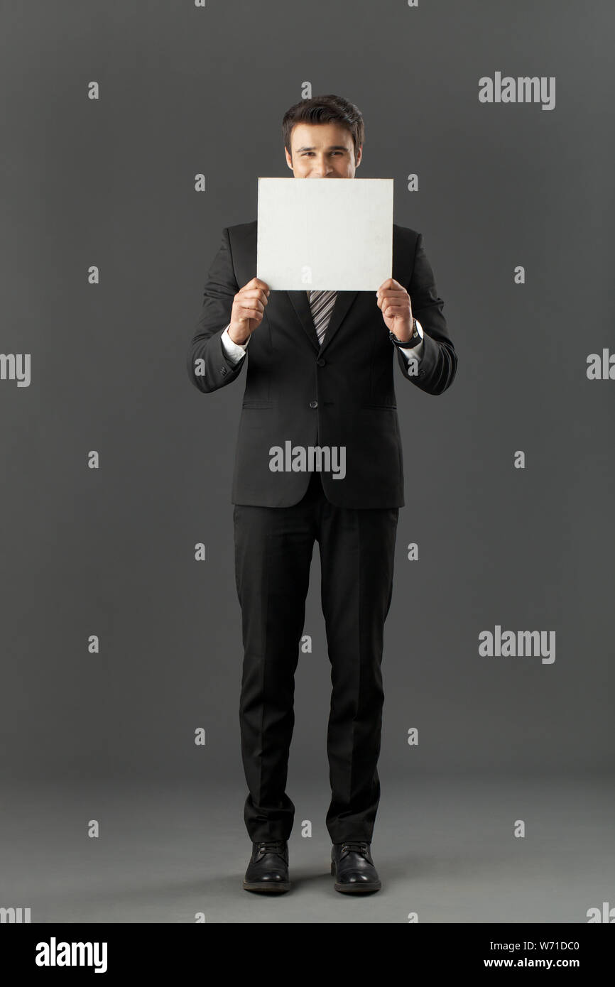 Businessman hiding behind a placard Stock Photo
