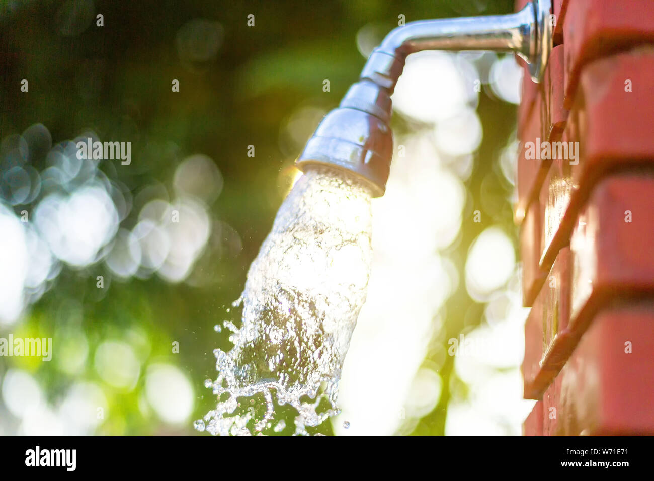 Water runs out of the shower on a red brick wall, outdoor shower after