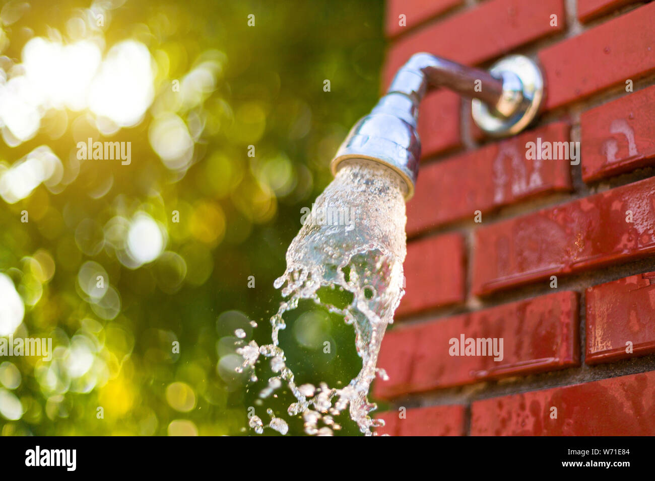 Water runs out of the shower on a red brick wall outdoor shower after