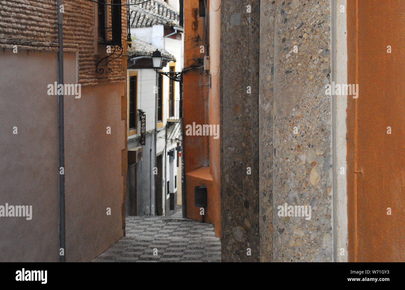 The Medieval section of Granada, Spain and a charming walkway through the narrow gap between apartment buildings. Note the pattern of the pavement. Stock Photo
