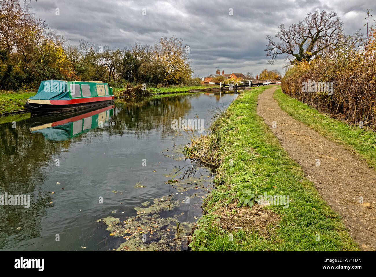 narrow boat moored on the restored section of Grantham Canal near the Woolsthorpe Lock in the Vale of Belvoir during Autumn with towpath to the side Stock Photo