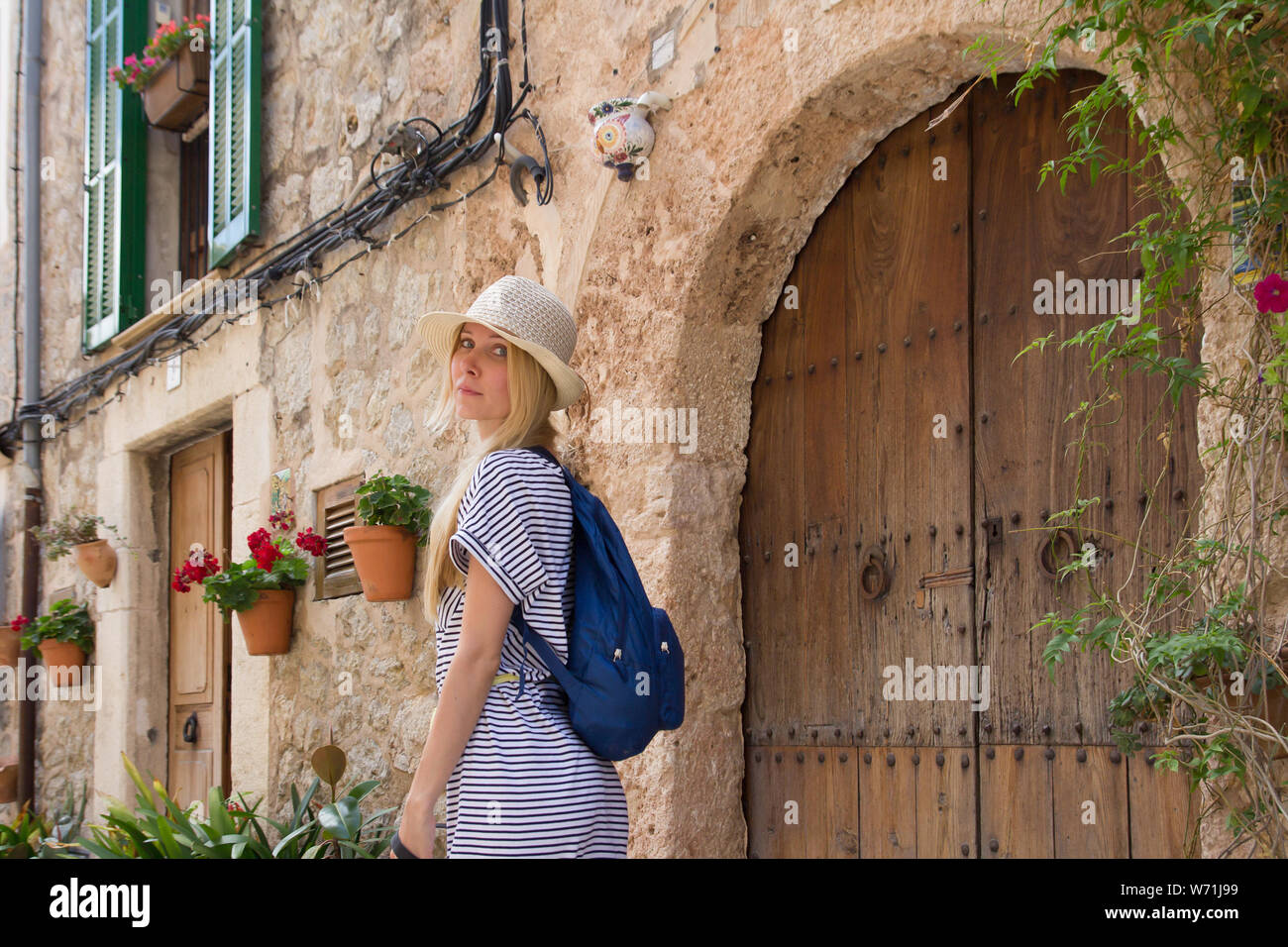 woman tourist wearing summer hat posing on street in mediterranean town in summer season Stock Photo