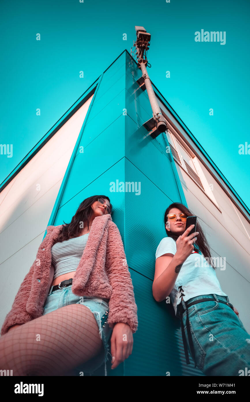 Two young female friends using mobile phone low angle shot Stock Photo