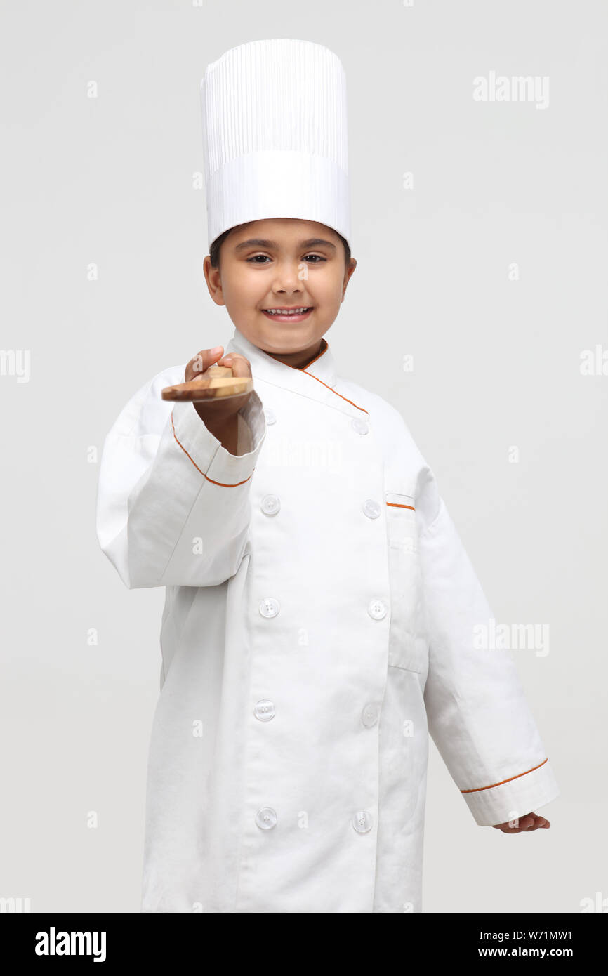 Child chef holding a wooden spatula Stock Photo