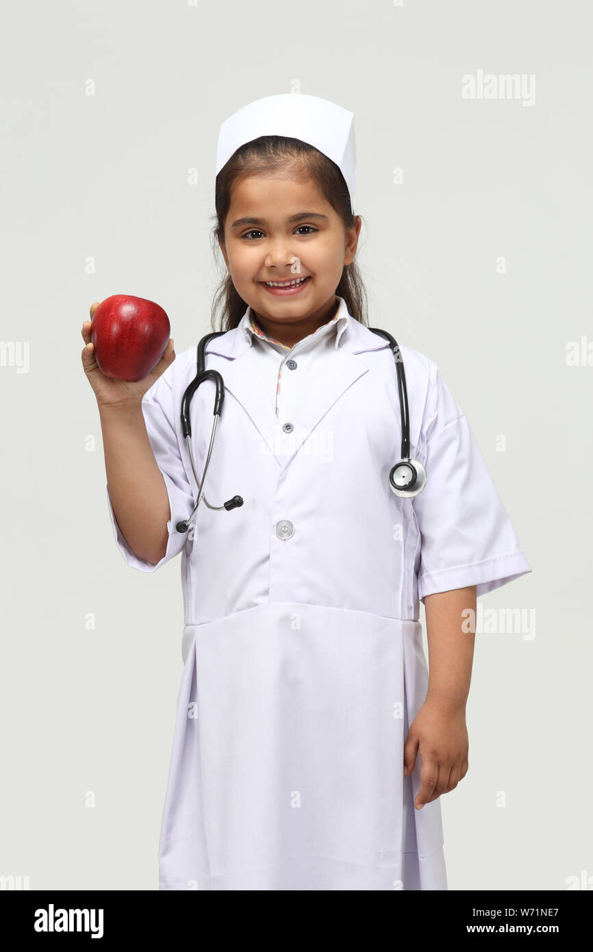 Girl dressed up as a nurse recommending an apple Stock Photo