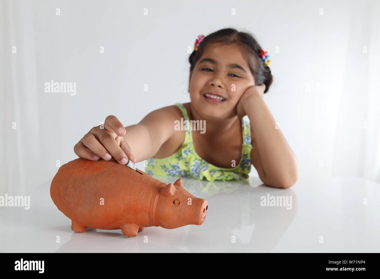 Girl inserting coin into a piggy bank Stock Photo - Alamy