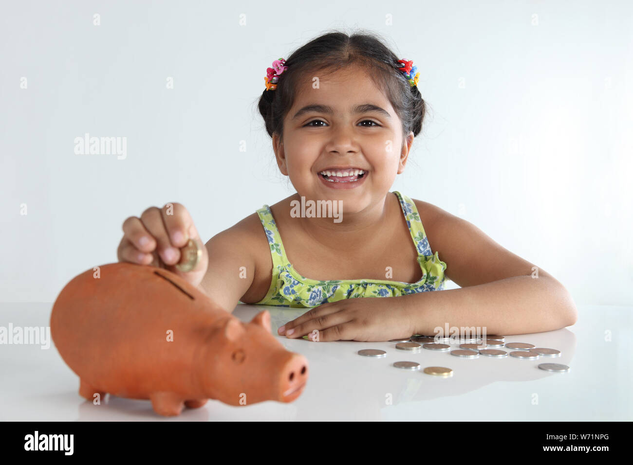 Girl inserting coin into a piggy bank and smiling Stock Photo - Alamy