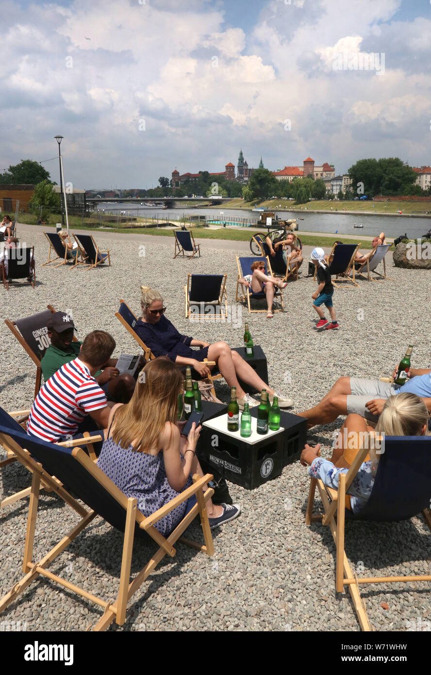 Cracow. Poland. People resting on the artificial beach made for the customers of the restaurant. Wawel Royal Castle across the river in the background Stock Photo