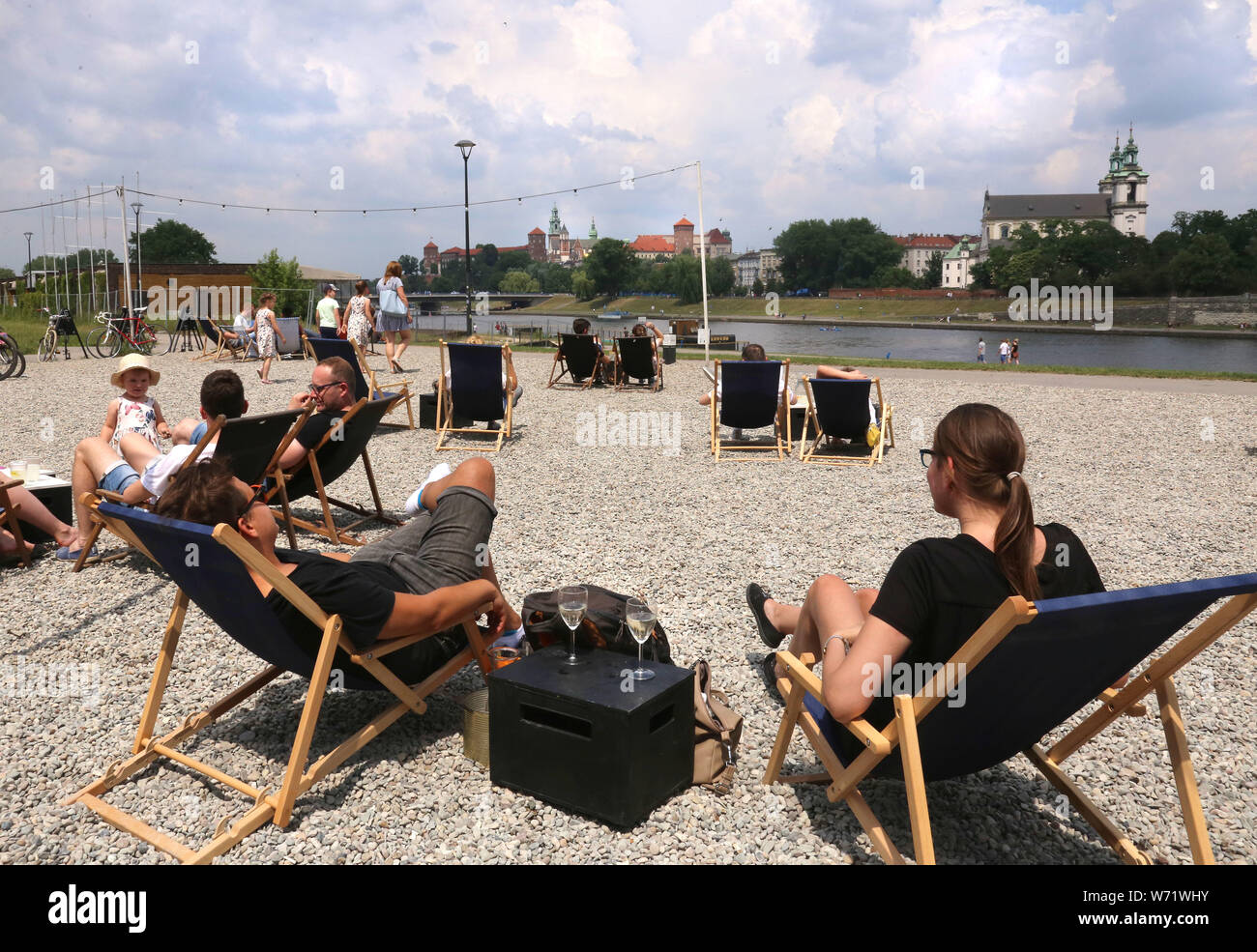 Cracow. Poland. People resting on the artificial beach made for the customers of the restaurant. Wawel Royal Castle across the river in the background Stock Photo