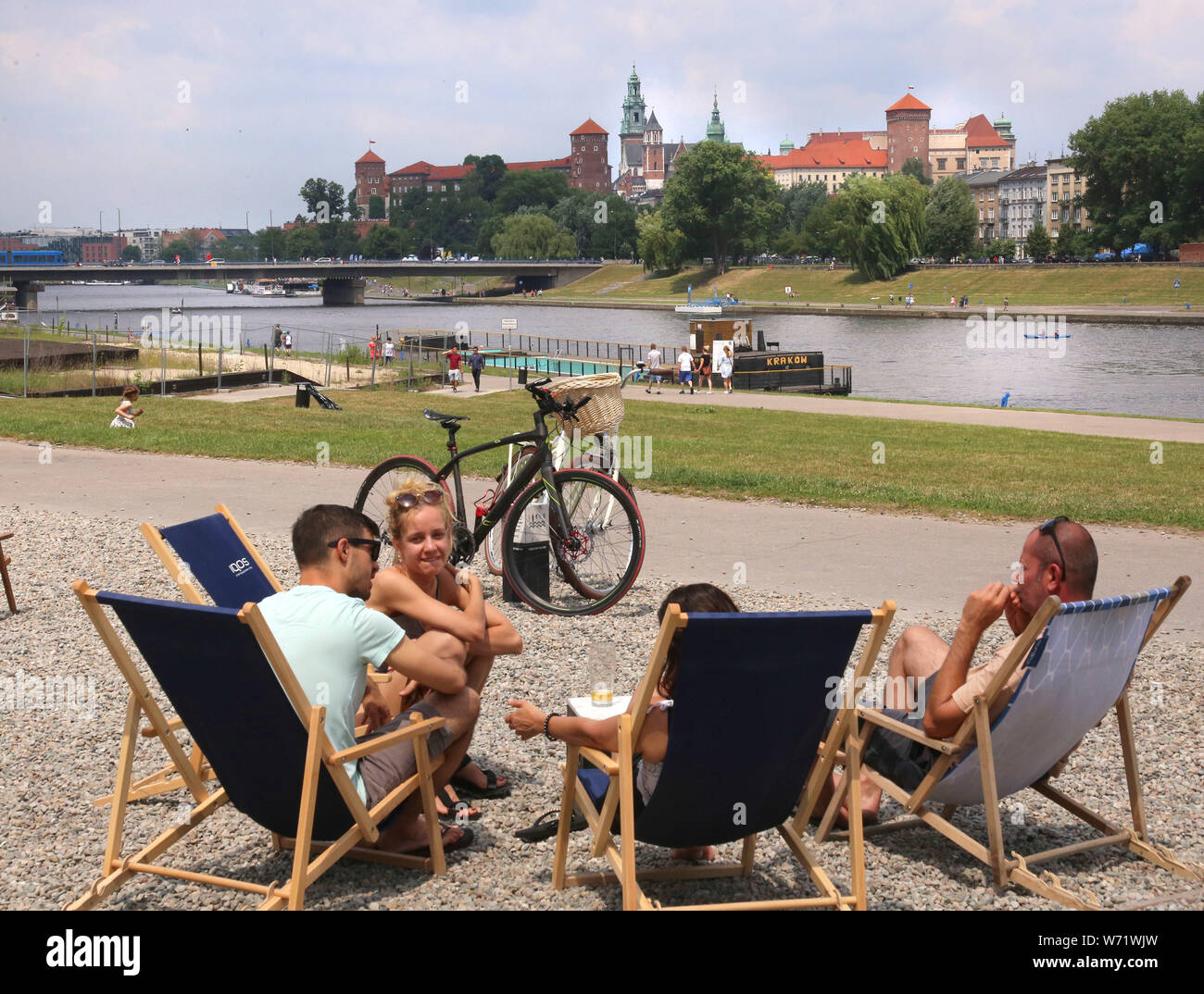 Cracow. Poland. People resting on the artificial beach made for the customers of the restaurant. Wawel Royal Castle across the river in the background Stock Photo