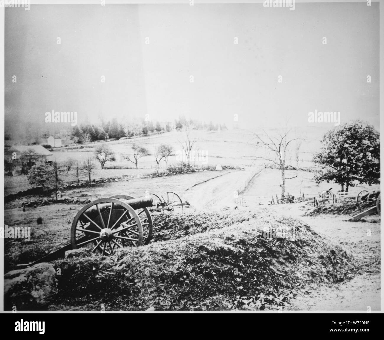 Barlows' Knoll after first day's battle, Gettysburg, Pennsylvania, northwest of town. July 1, 1863., ca. 1960 - ca. 1997; General notes:  Inaccurately-titled/dated image of Battle of Gettysburg artillery lunettes on en:Stevens Knoll with unattended postbellum cannon placed during the Gettysburg Battlefield commemorative era near Slocum Avenue (center), which turns westward to the Baltimore Pike (background).  Cemetery Hill (background) has faint image of the en:Evergreen Cemetery gatehouse along the Pike with the gatehouse archway depicted darker than the roofline and towers.  Slocum Av was bu Stock Photo