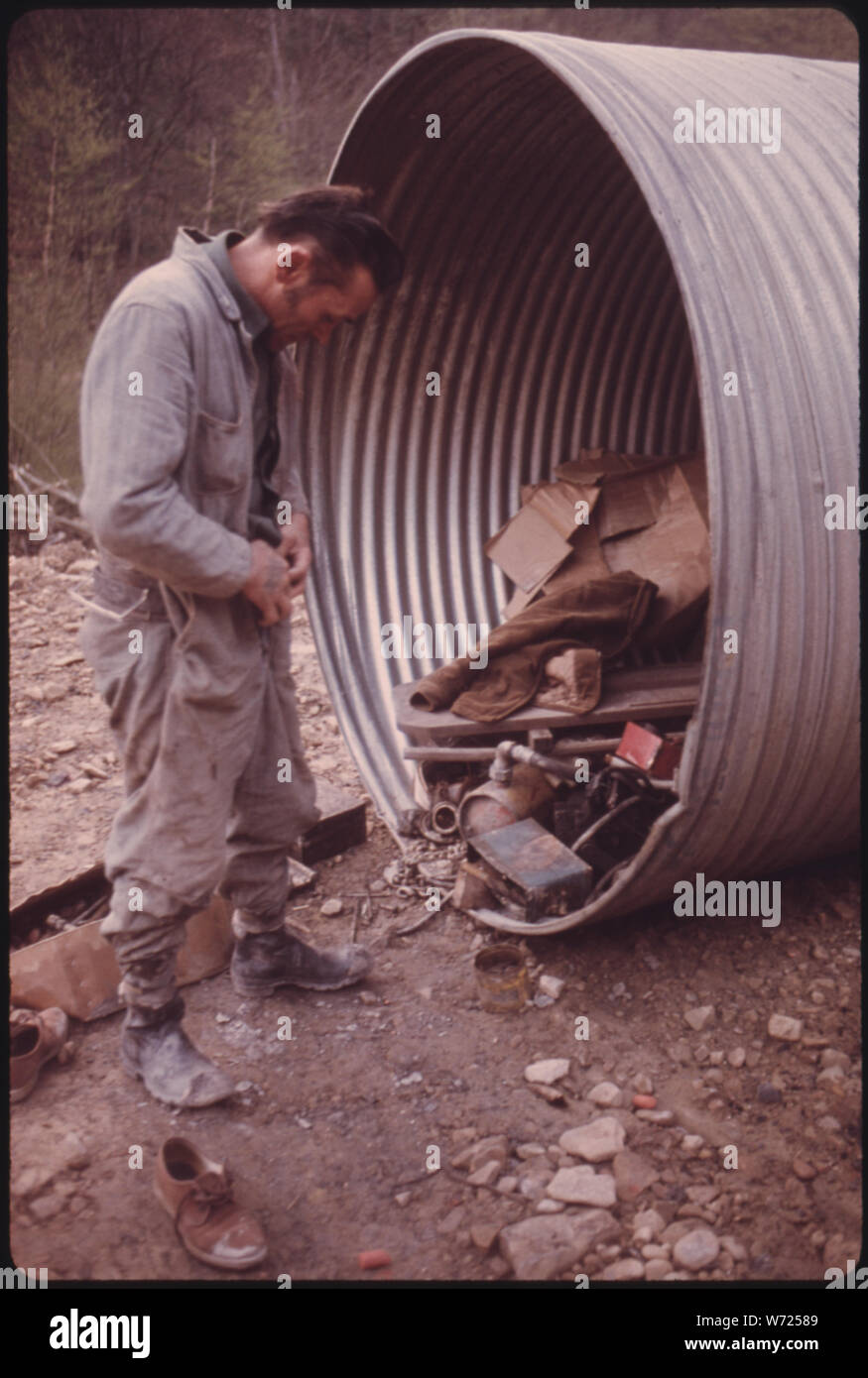 DOREN BISHOP, SUPERINTENDENT FOR ROBIN MINES OWNED BY THE ALMA COAL CORPORATION NEAR CLOTHIER AND MADISON, WEST VIRGINIA PUTS ON MINING COVERALLS NEXT TO A METAL CULVERT. HE IS SUPERVISING A NEW MINE WHICH HASN'T YET GONE INTO PRODUCTION, AND THE MINER SHOWER ROOMS ARE NOT FINISHED Stock Photo