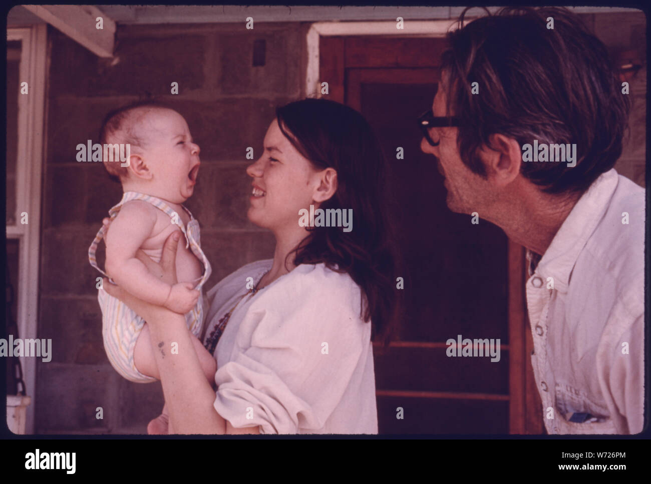 ERNEST WATKINS LOOKS AT ONE OF HIS GRANDCHILDREN HELD BY HIS 