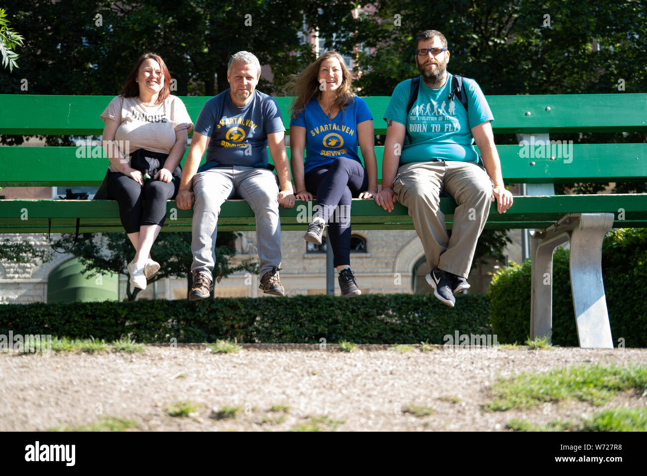 People sitting on an oversize park bench in Orebro, Sweden. Art installation from OpenArt 2015, 'Park Bench' by Lilian Bourgeat Stock Photo