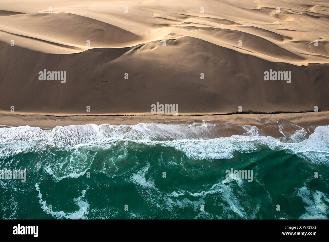 Aerial view of Skeleton coast sand dunes meeting the waves of Atlanic ocean. Skeleton coast, Namibia. Stock Photo
