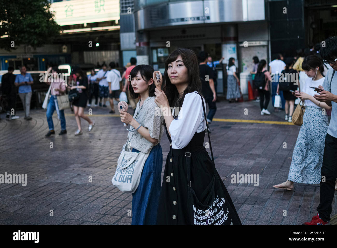 Women hold small portable fans at the Shibuya crossing in Tokyo.A ...