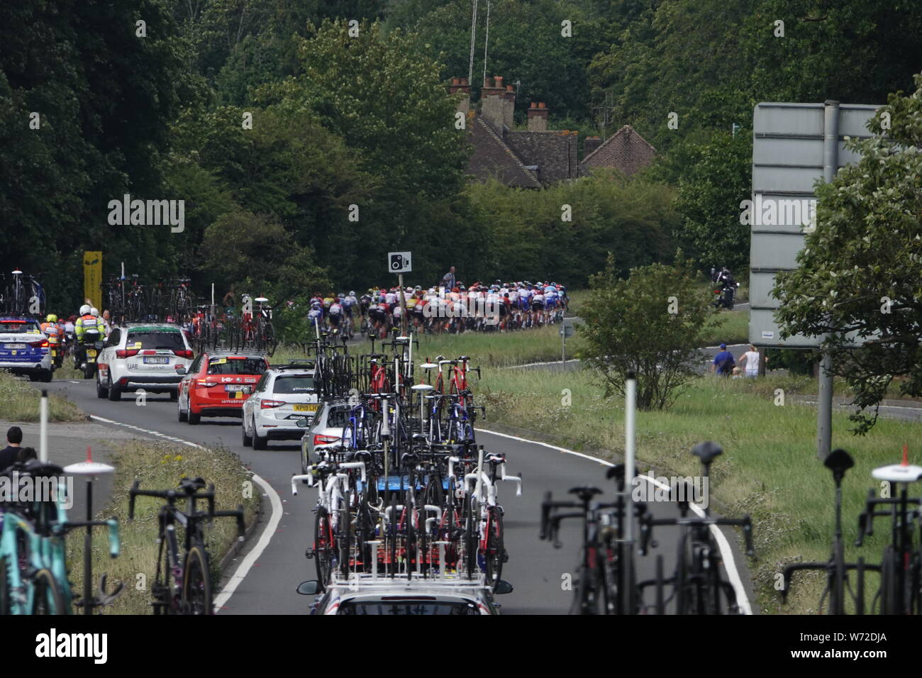 Surrey, UK. 04th Aug, 2019.   The peleton of cyclists and their support crews racing in the Prudential Ride London/Surrey Classic for Pro riders round the bend on the A24 outside Debies Vineyard in Dorking . Credit: Motofoto/Alamy Live News Stock Photo
