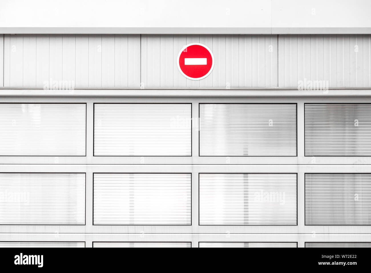 No entry traffic sign on gray industrial wall, minimalist architecture with warning road sign, red color pop up Stock Photo