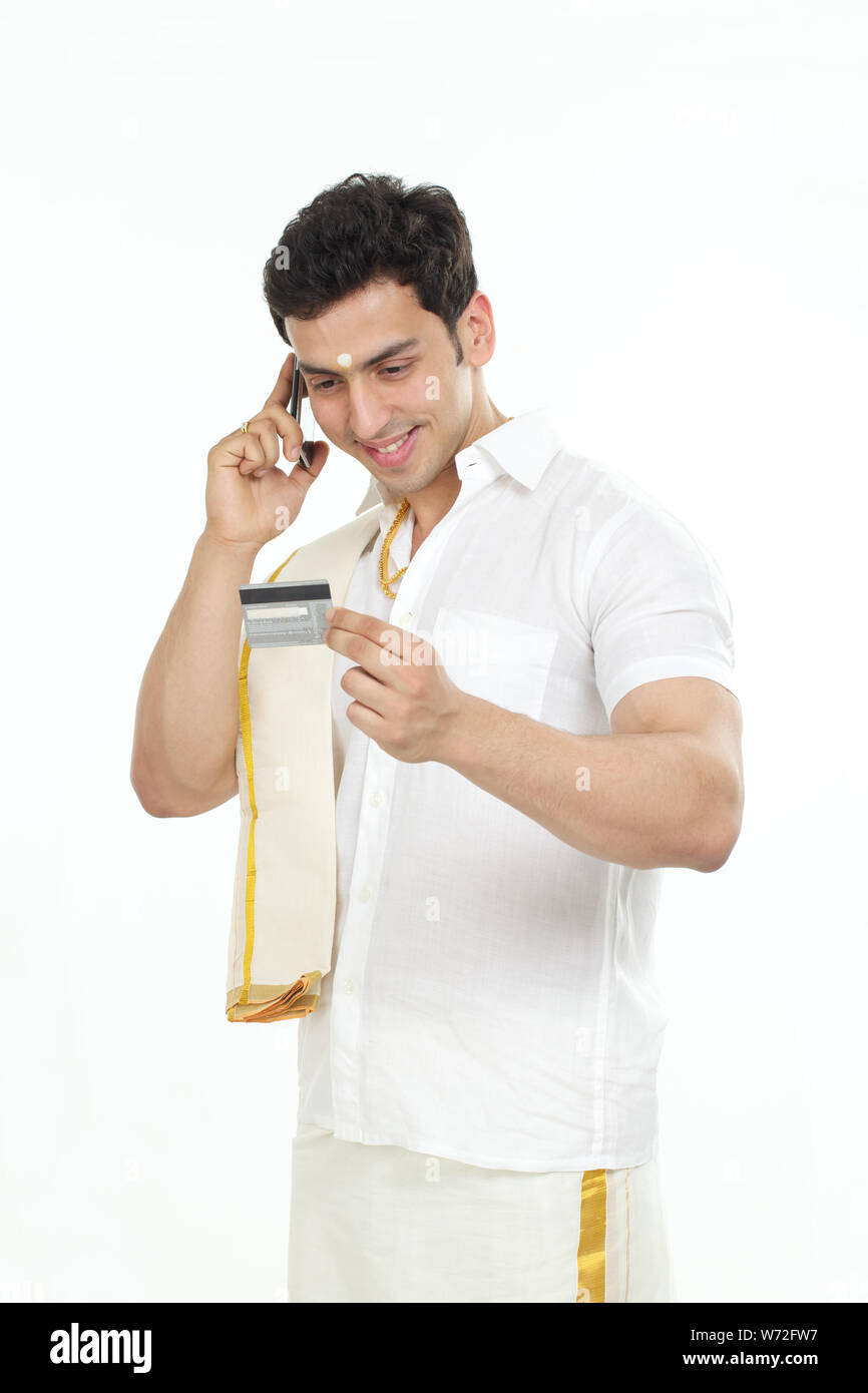 South Indian man talking on a mobile phone and holding credit card ...