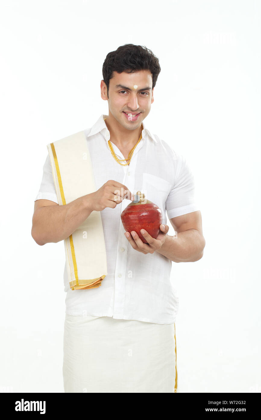 South Indian man inserting a coin into a piggy bank Stock Photo - Alamy