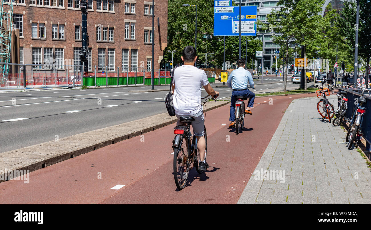 Rotterdam, Netherlands. June 28 2019. Back view of people riding bikes in the city center, Spring sunny day Stock Photo