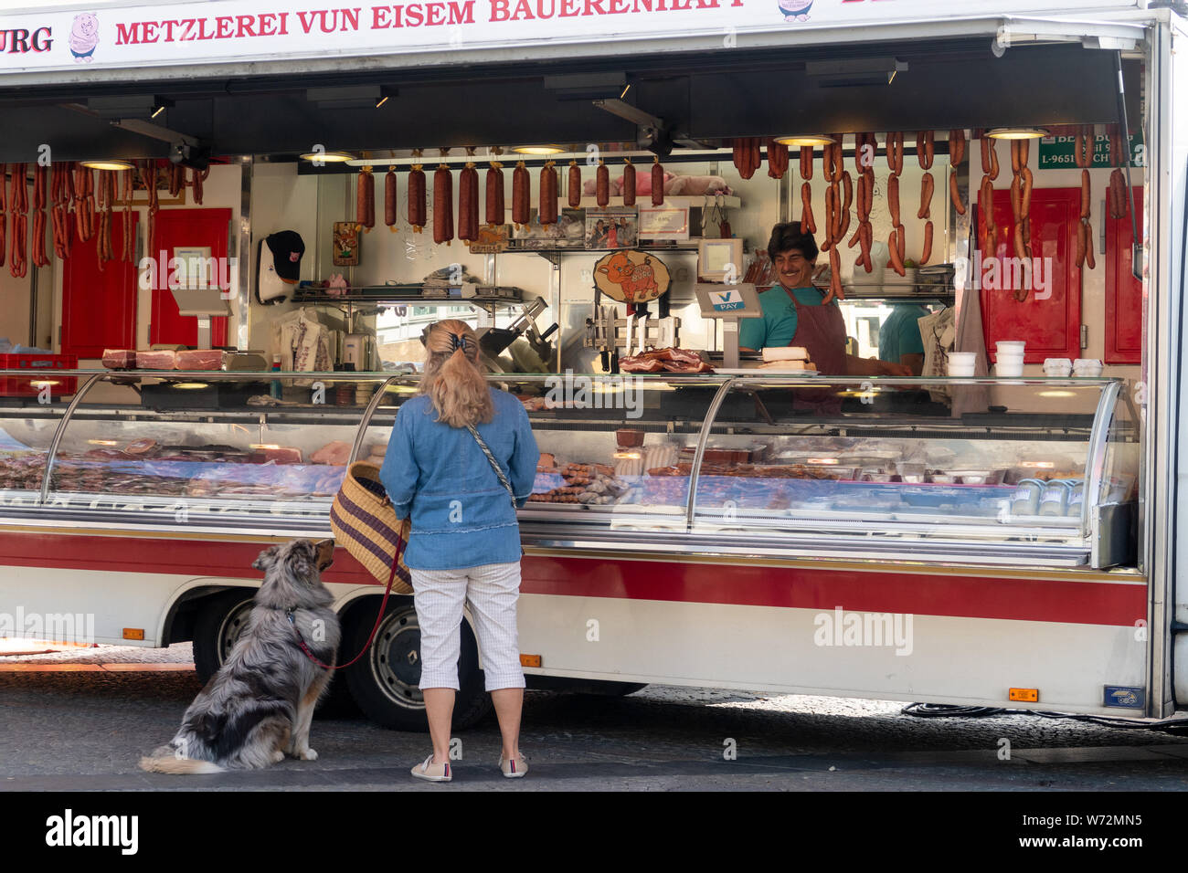 A woman with Scotch Collie at the meat stall in the the market in the Place Guillaume II in Luxembourg. Stock Photo