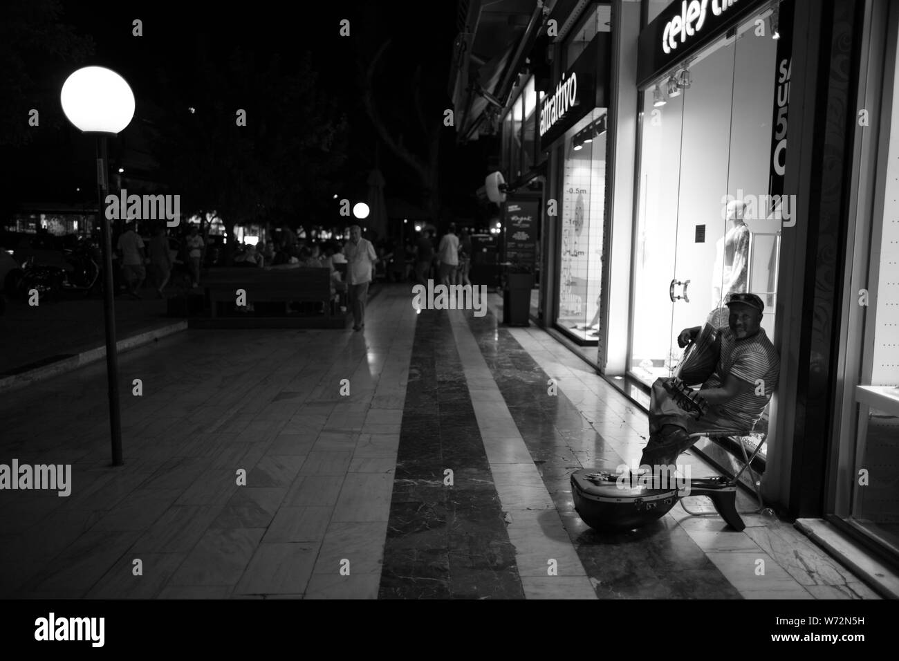 Glyfada, Athens Greece. A musician playing in the city's commercial centre at night. Stock Photo