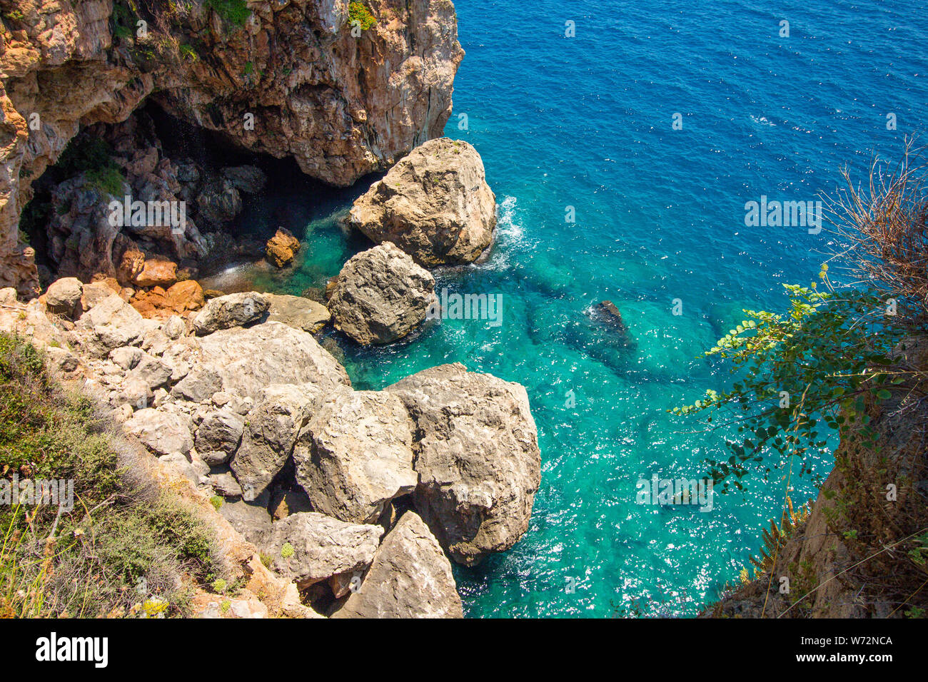 Top view of the rock and blue sea water. In the rock there is a large cave which is flooded with sea water Stock Photo