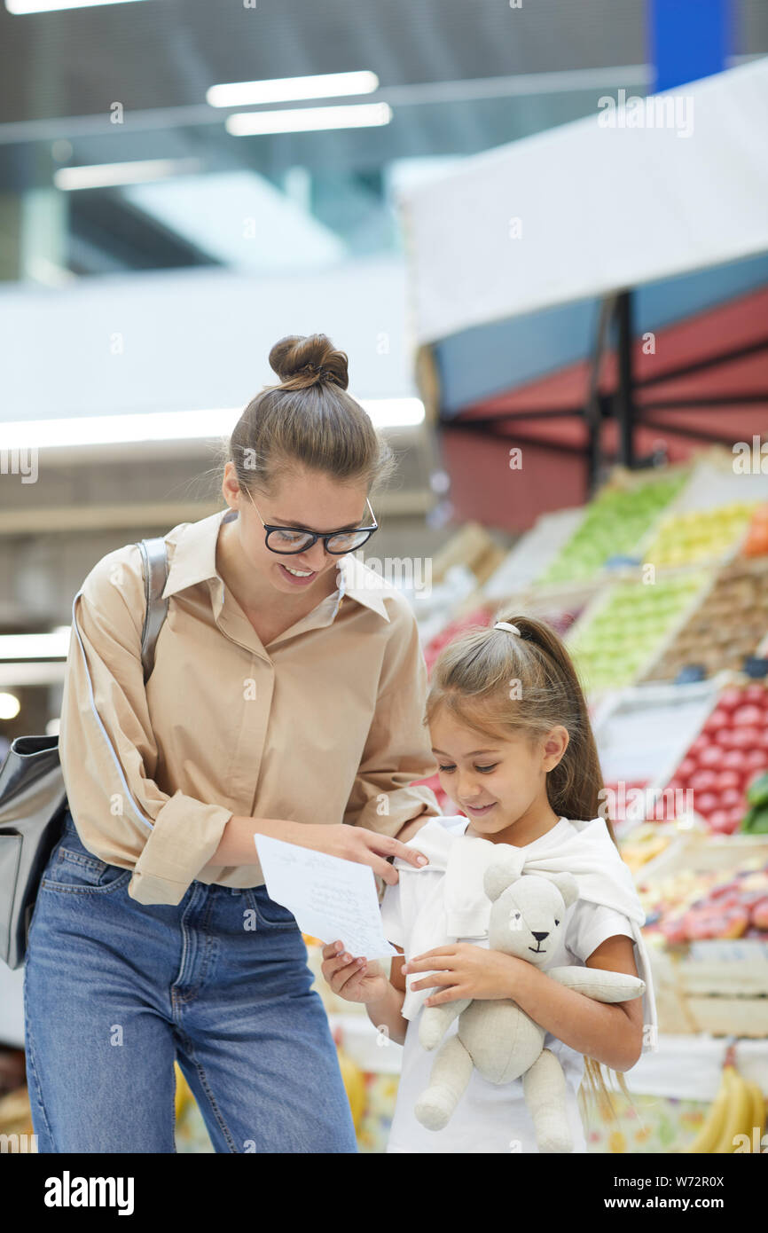 Portrait of contemporary young woman shopping at farmers market with cute daughter Stock Photo