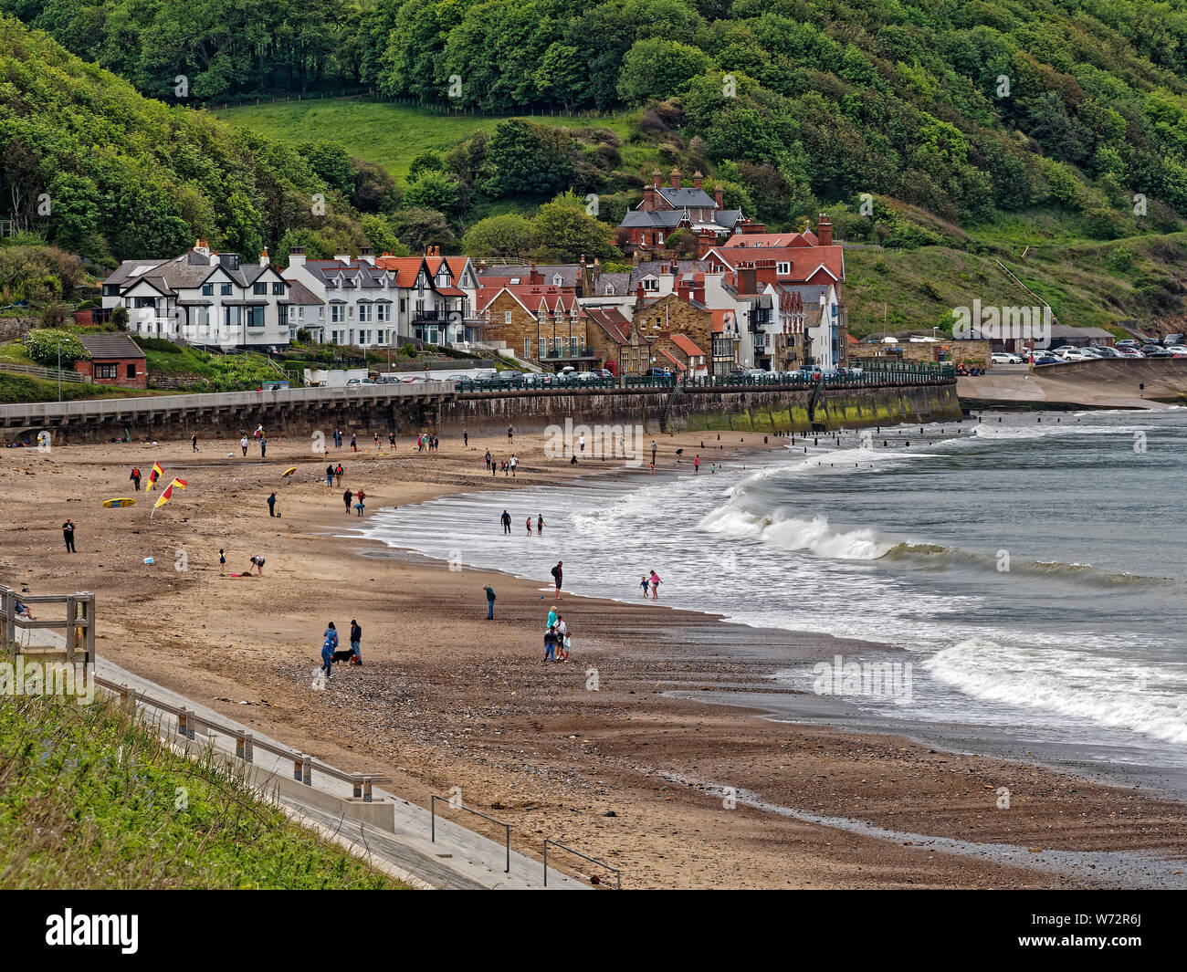 Sandsend on the North Yorkshire Coast with visitors enjoying the beach with waves crashing along it Stock Photo
