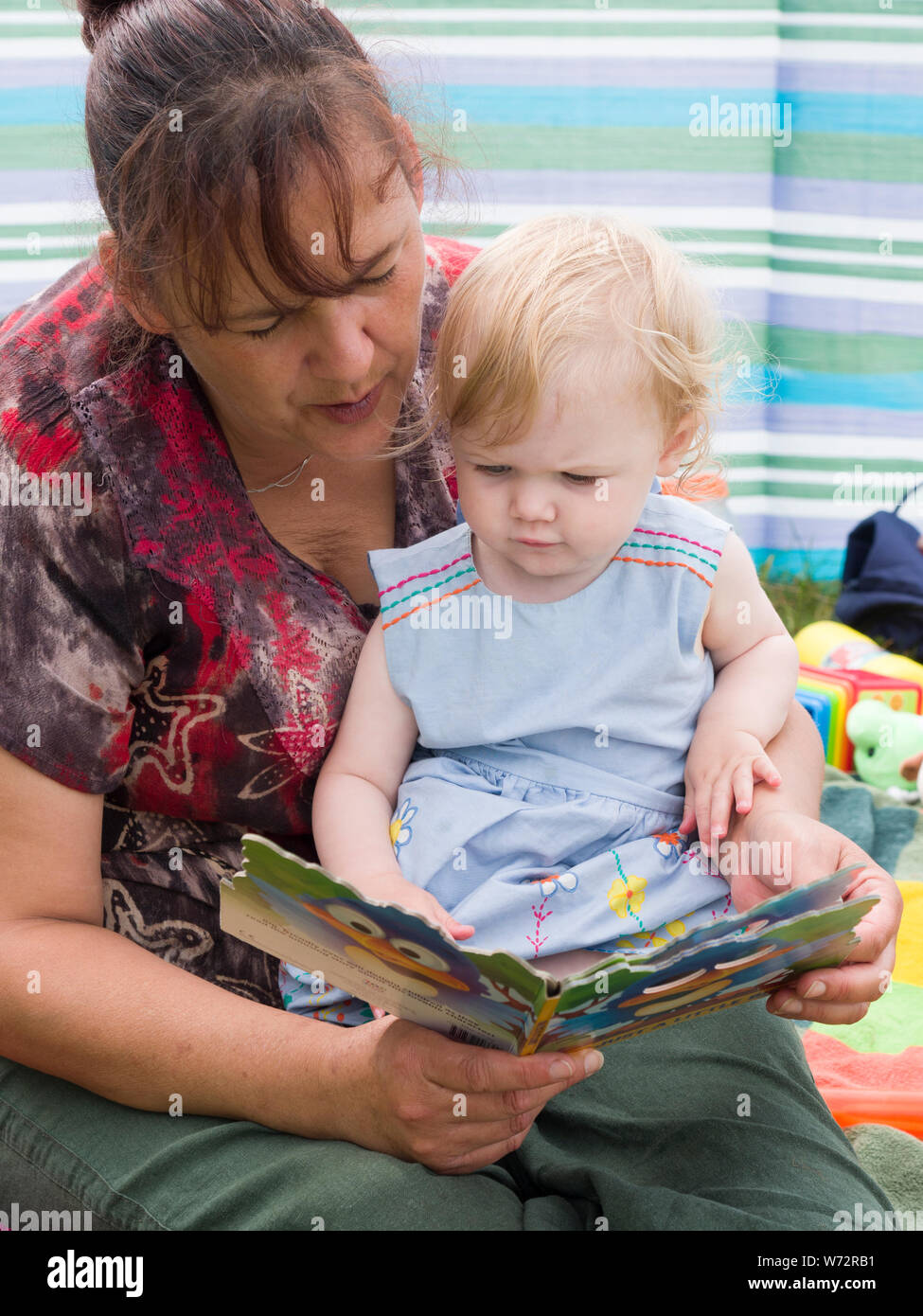 one year old reading a book with her granny, UK Stock Photo
