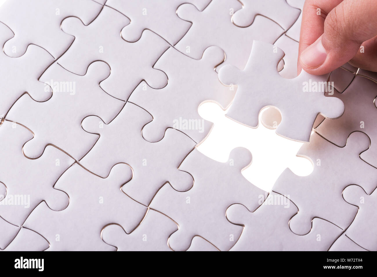 Connection concept : Hand holding pieces of jigsaw puzzle and insert into the missing hole Stock Photo