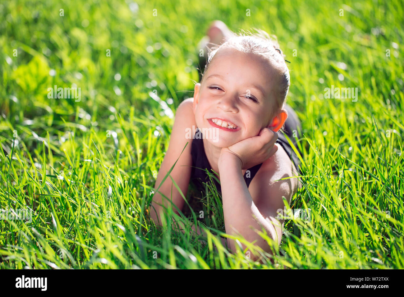 cute happy little girl lying on the grass. Stock Photo