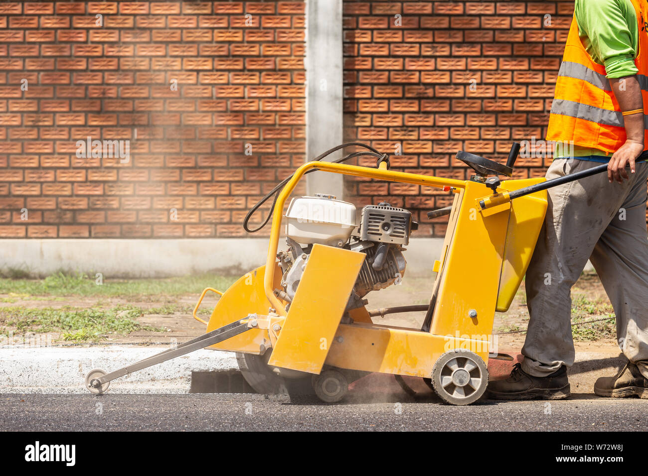 Outdoor working : Worker using machine to cut the asphalt road. Process of building new road Stock Photo