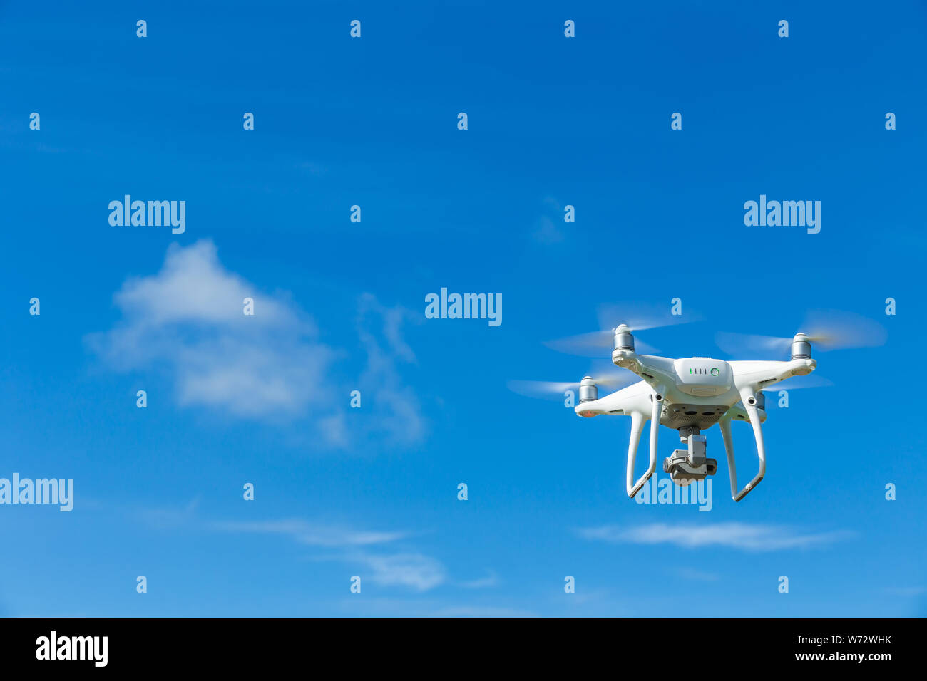 Flying drone quadcopter with digital camera on blue sky background Stock Photo