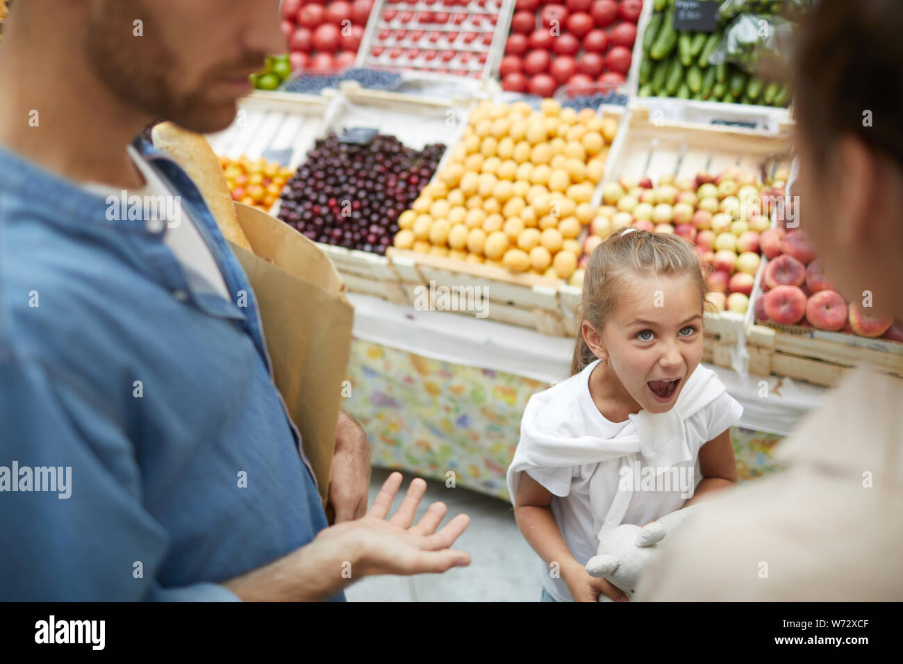 High angle view at spoiled little girl screaming at parents in supermarket, copy space Stock Photo