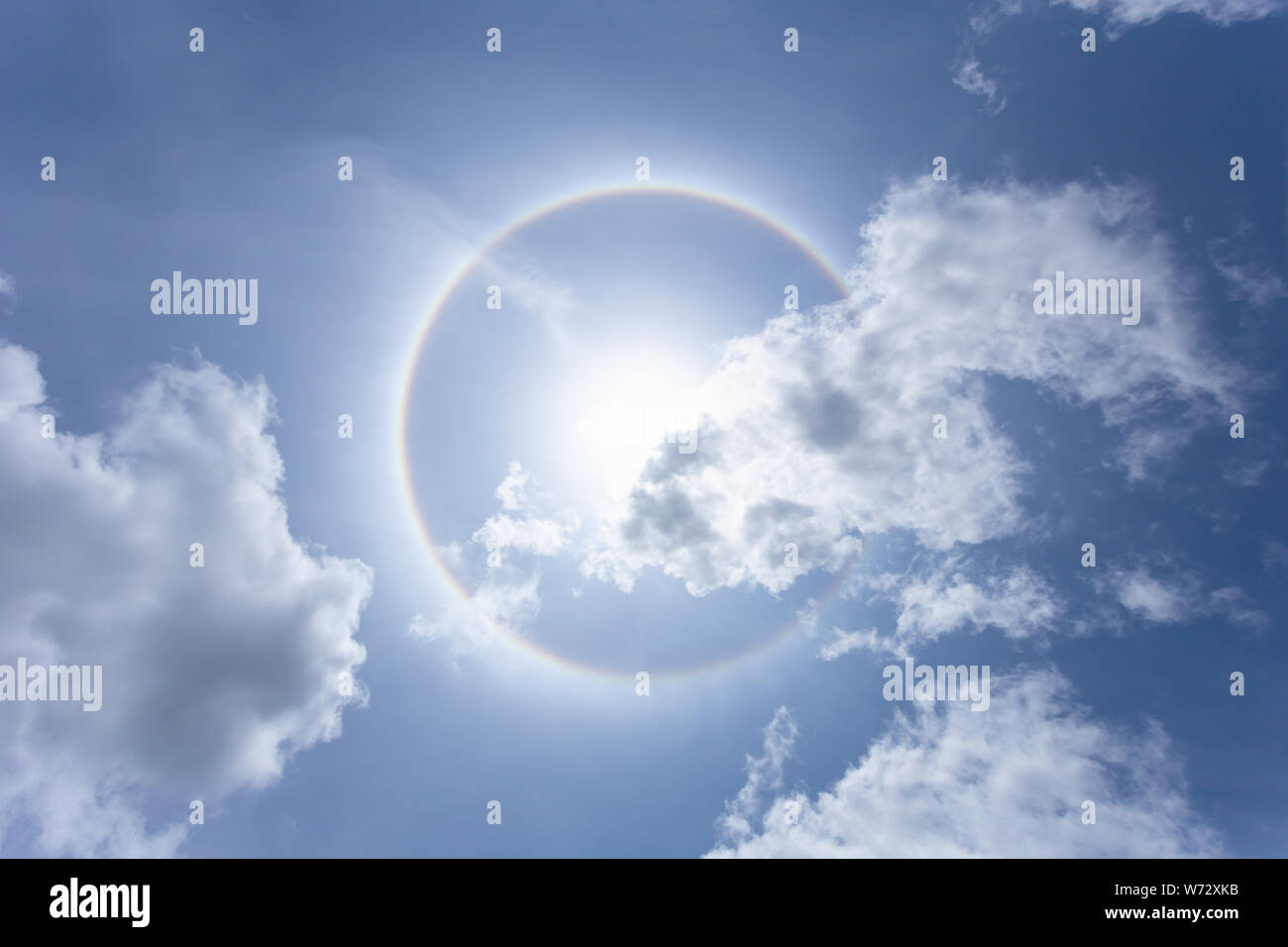 Sun with circular rainbow in day time or Sun halo on blue sky background with cloud Stock Photo