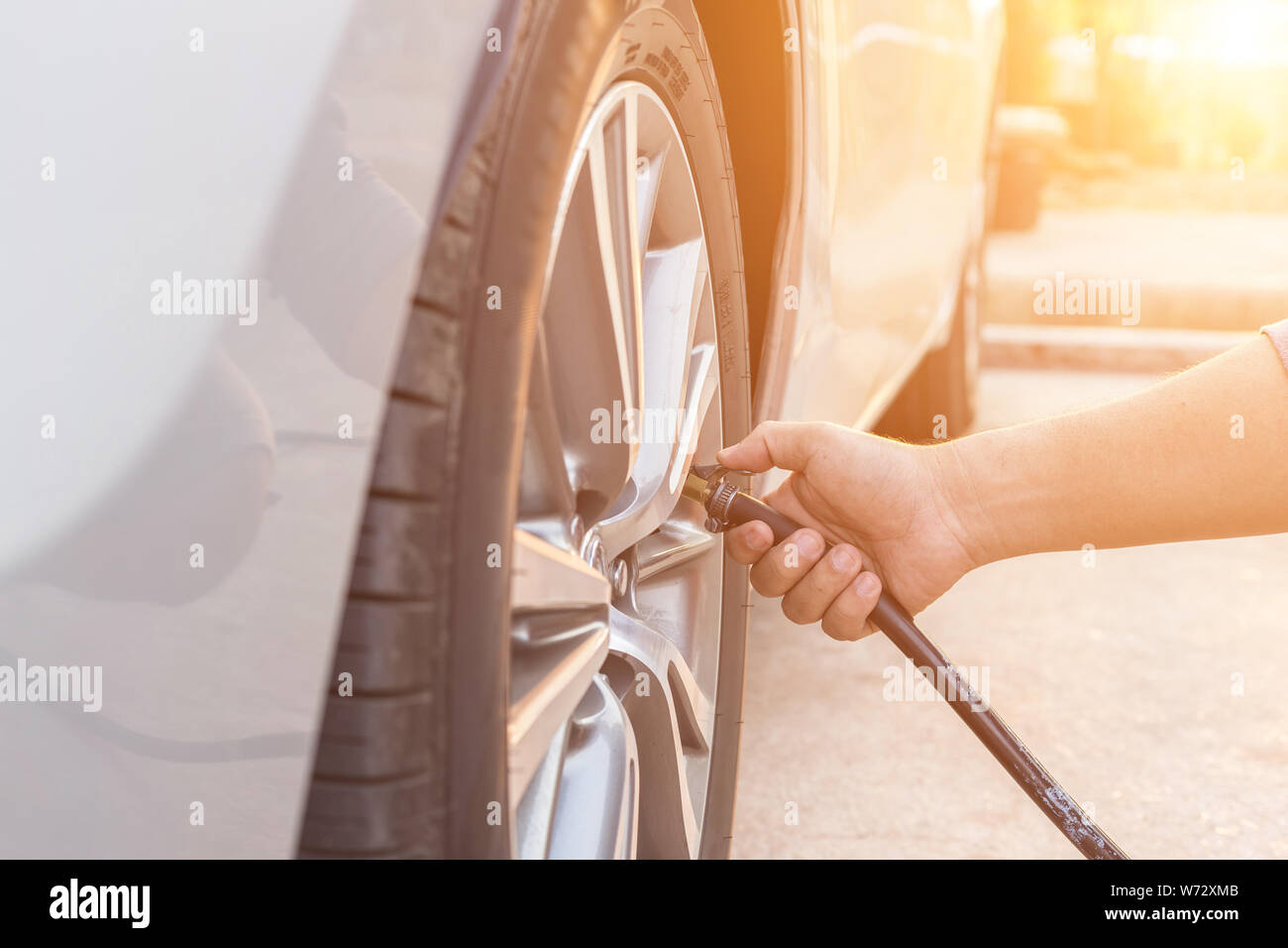 Man checking air pressure and filling air in the tires of his car Stock Photo