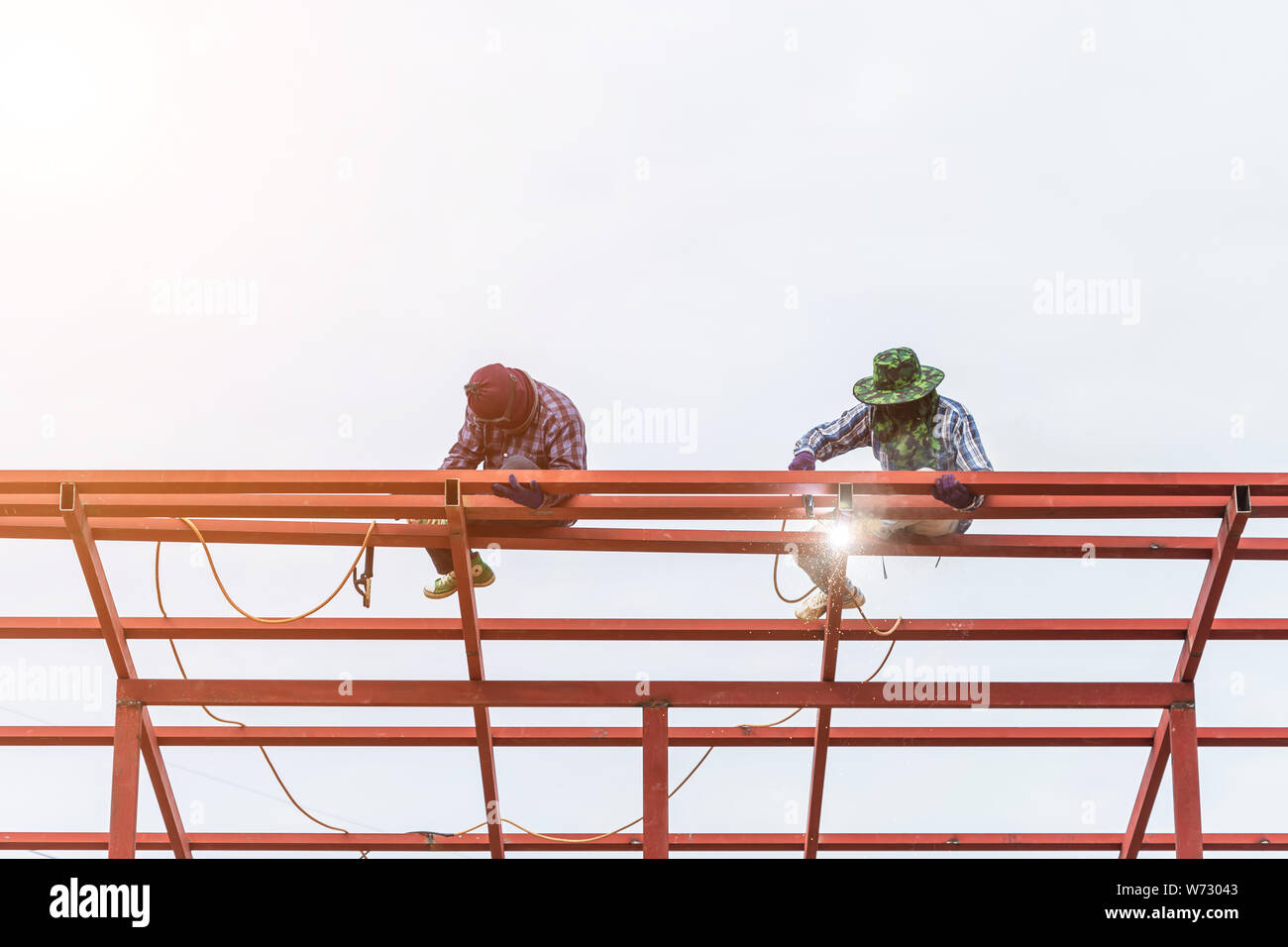 Construction worker welding steel for roof structure in process of house building Stock Photo