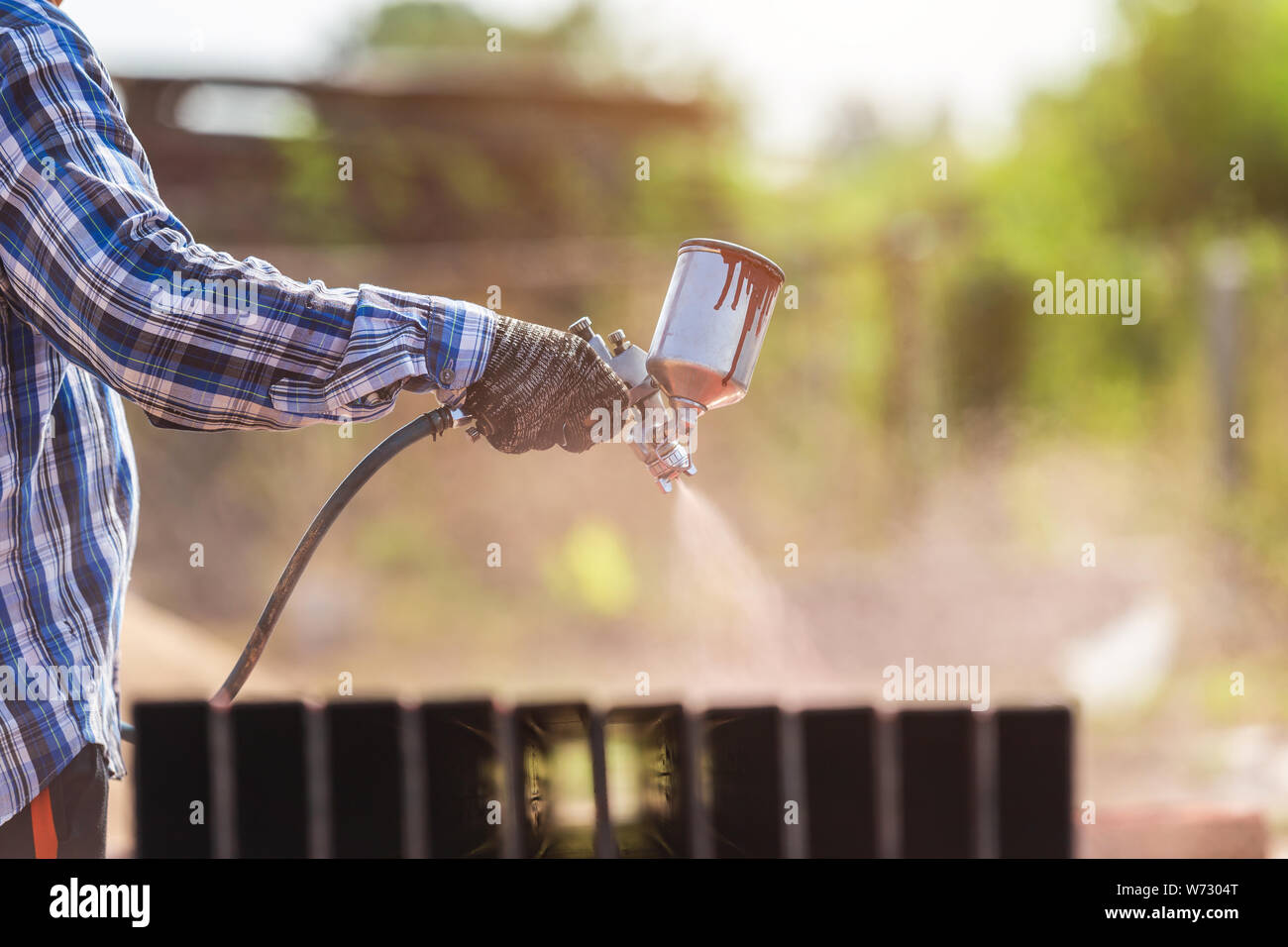 Construction worker spraying paint to steel pipe to prevent the rust on the surface Stock Photo