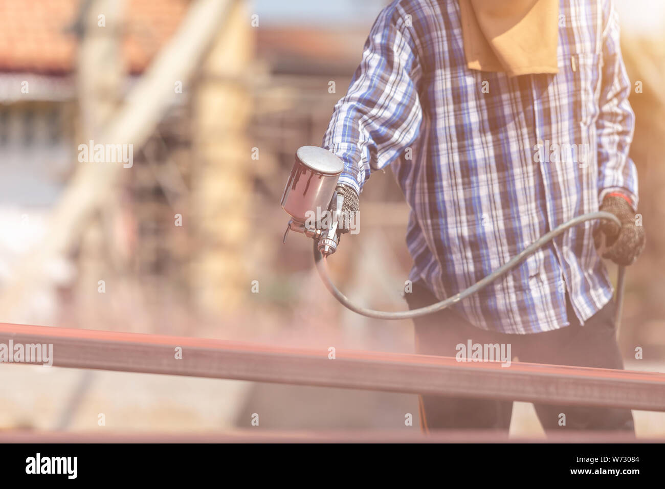 Construction worker spraying paint to steel pipe to prevent the rust on the surface Stock Photo